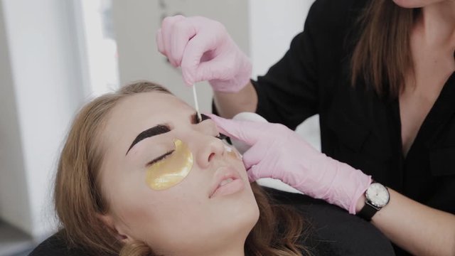 Professional makeup artist removes eyebrow paint to client.