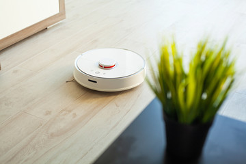 Robot vacuum cleaner performs automatic cleaning of the apartment at a certain time. Smart home.