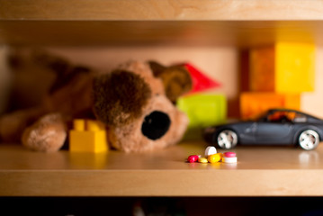 Pills on the background of children's toys lies on a shelf. Selective Focus - Defocused Toys
