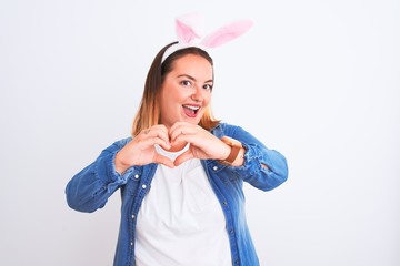 Young beautiful woman wearing banny ears standing over isolated white background smiling in love showing heart symbol and shape with hands. Romantic concept.