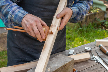 a old carpenter working with wood outdoors during summer day