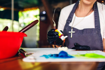 Confectioner girl adds a drop of dye to cake cream.