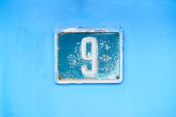 Number 9, digit nine, dark blue plate on light blue background.