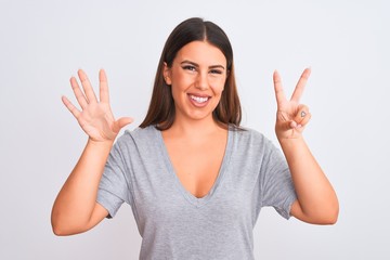 Portrait of beautiful young woman standing over isolated white background showing and pointing up with fingers number seven while smiling confident and happy.
