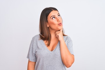 Portrait of beautiful young woman standing over isolated white background with hand on chin thinking about question, pensive expression. Smiling with thoughtful face. Doubt concept.