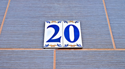 Number 20, twenty, blue digits on decorative tiles.