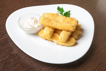 Cheese sticks breaded, with sauce and herbs, on a platter.