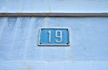 Number 19, nineteen, blue plate on light weathered background.