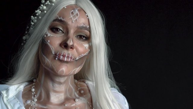 waking nightmare, story of young beautiful dead bride, young wife in white dress with blond long straight hair in room with black walls posing for camera, creative Halloween pearl makeup