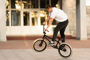 The guy rides on the BMX, standing on the rear wheel.