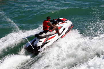 Obraz premium Angled overhead view of a man running waves on a speeding jet ski.