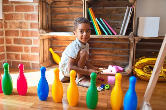 Beautiful african american toddler playing with cars and skittles at kindergarten