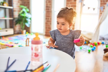 Beautiful toddler playing with building blocks toys at kindergarten