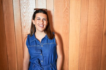 Fototapeta premium Young beautiful woman smiling happy and positive over wooden wall
