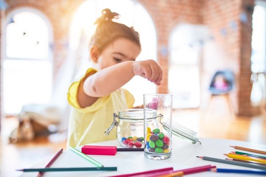 Beautiful toddler standing playing with chocolate colored balls on the table at kindergarten