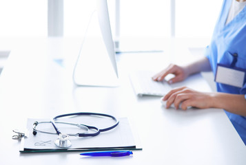 Beautiful young smiling female doctor sitting at the desk