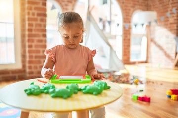 Beautiful blond toddler girl drawing using digital board at kindergarten