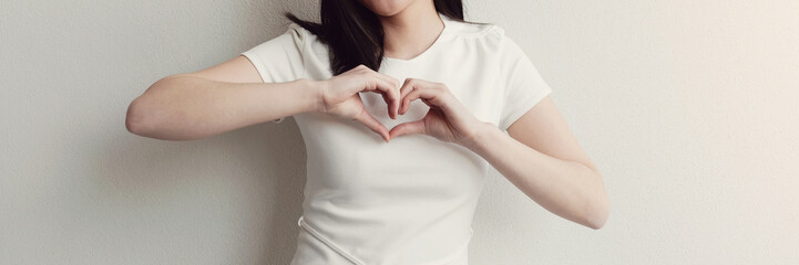 Happy Asian young woman making her hands in heart shape, hope, heart health insurance, social...