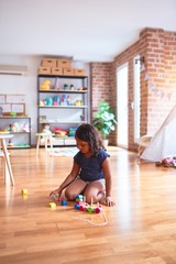 Beautiful toddler girl sitting on the floor playing with train at kindergarten