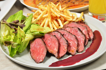 Roasted beef with french fries and salad on white plate 