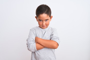 Beautiful kid boy wearing grey casual t-shirt standing over isolated white background skeptic and nervous, disapproving expression on face with crossed arms. Negative person.