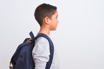 Beautiful student kid boy wearing backpack standing over isolated white background looking to side,...