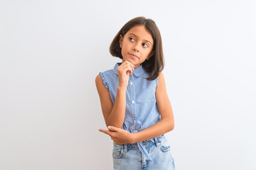 Young beautiful child girl wearing blue casual shirt standing over isolated white background with...