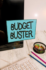 Conceptual hand writing showing Budget Buster. Concept meaning Carefree Spending Bargains Unnecessary Purchases Overspending Note paper taped to black screen near keyboard stationary