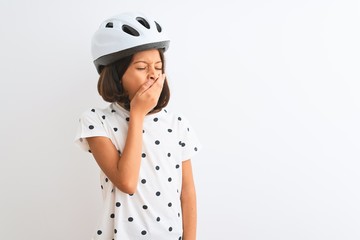 Beautiful child girl wearing security bike helmet standing over isolated white background bored yawning tired covering mouth with hand. Restless and sleepiness.