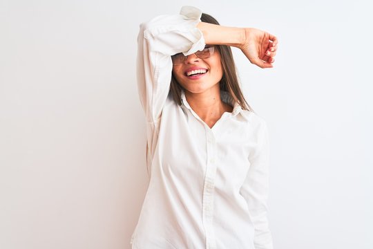 Young beautiful businesswoman wearing glasses standing over isolated white background covering eyes with arm smiling cheerful and funny. Blind concept.