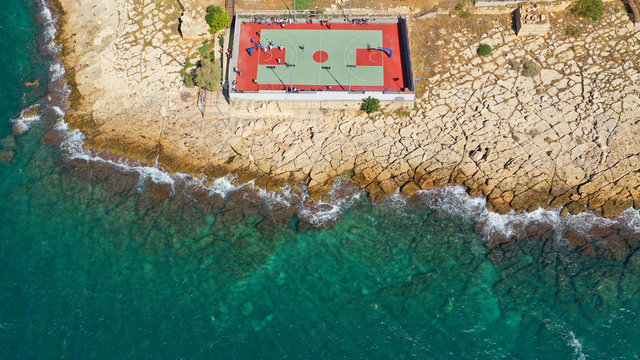 Aerial top down photo of seaside outdoor basketball court with team competing in Mediterranean popular destination