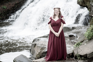 Teen Girl in a red dress by waterfall