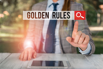 Word writing text Golden Rules. Business photo showcasing basic principle that should always follow to ensure success Female business person sitting by table holding mobile phone
