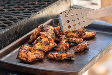 Smoked chicken wings piled on a serving tray next to a bbq smoker