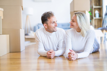 Fototapeta premium Young beautiful couple lying down on the floor at new home around cardboard boxes