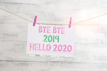 Writing note showing Bye Bye 2019 Hello 2020. Business concept for Starting new year Motivational message 2019 is over Clothesline clothespin rectangle shaped paper reminder white wood desk