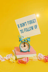 Text sign showing 8 Don T Forget To Follow Up. Business photo showcasing asking someone to keep connection with others Alarm clock sticky note paper balls stacked notepads colored background