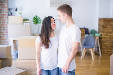 Fototapeta premium Young beautiful couple standing at new home around cardboard boxes