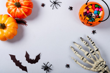Fototapeta premium Halloween and decoration concept, Pumpkins, bats, skeleton arm and candies on gray background.