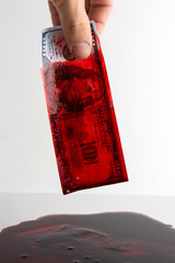 bloody business concept: blood flows from a banknote of 100 dollars