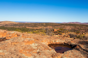 Fototapeta na wymiar Pool of water in granite rocks under a blue sky in the Australian outback