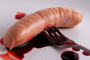 vegetarian propaganda, concept: bleeding sausage on a white plate, short focus