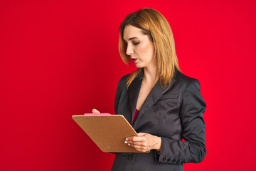 Young beautiful redhead businesswoman wearing suit writing on flip board