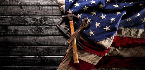 Old and worn work tools on large American flag - Labor day background