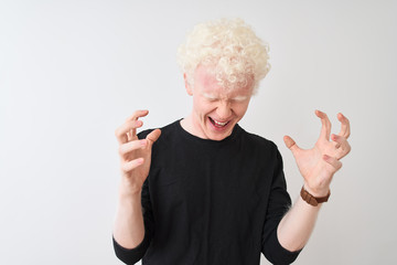 Young albino blond man wearing black t-shirt standing over isolated white background celebrating mad and crazy for success with arms raised and closed eyes screaming excited. Winner concept