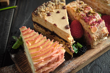 Different pieces of cakes on a wooden board . catering menu