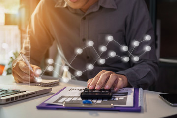 Male businessman or Designer using tablet with laptop and document on desk in modern office with virtual interface graphic icons network diagram.