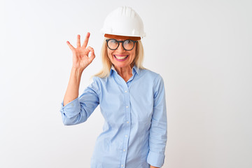 Middle age architect woman wearing glasses and helmet over isolated white background smiling positive doing ok sign with hand and fingers. Successful expression.
