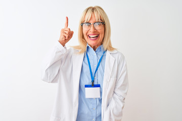 Middle age scientist woman wearing glasses and id card over isolated white background pointing finger up with successful idea. Exited and happy. Number one.