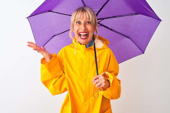 Middle Age Woman Wearing Rain Coat And Purple Umbrella Over Isolated White Background Very Happy And Excited, Winner Expression Celebrating Victory Screaming With Big Smile And Raised Hands